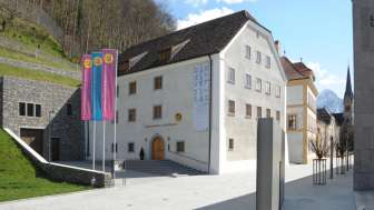 Exterior view of the Liechtenstein National Museum in Vaduz, featuring colorful flags and a view of the historic façade.