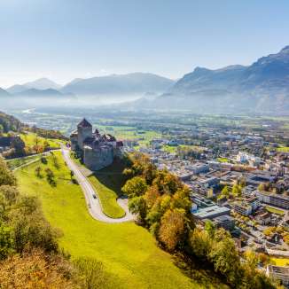 Aerial view of Vaduz Castle overlooking the city of Vaduz and the Rhine Valley on a clear autumn day